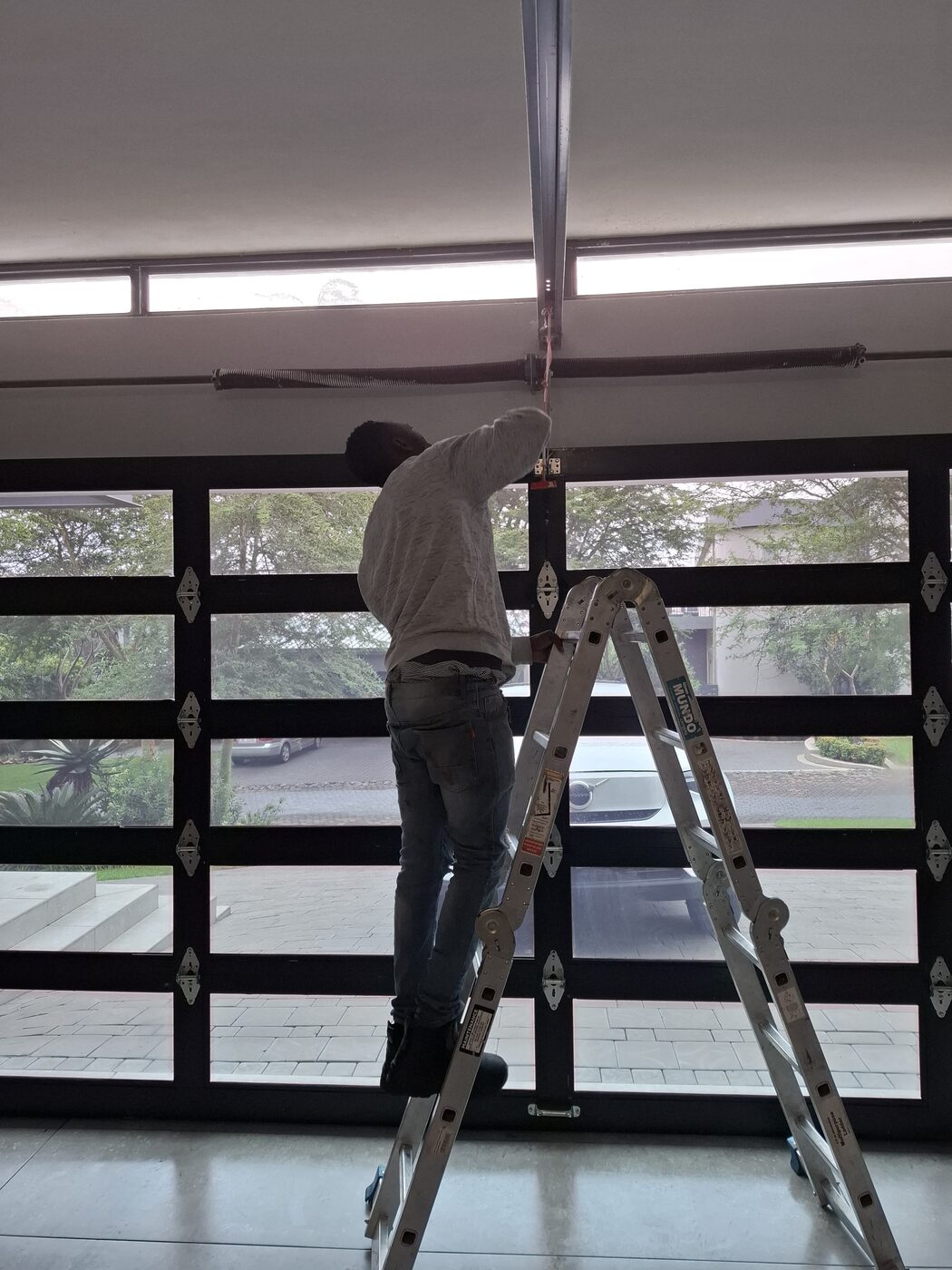 Technician fitting an automated garage door mechanism as part of a smart home installation