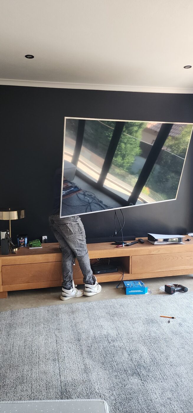 Technician mounting a large flat-screen TV on a living room accent wall